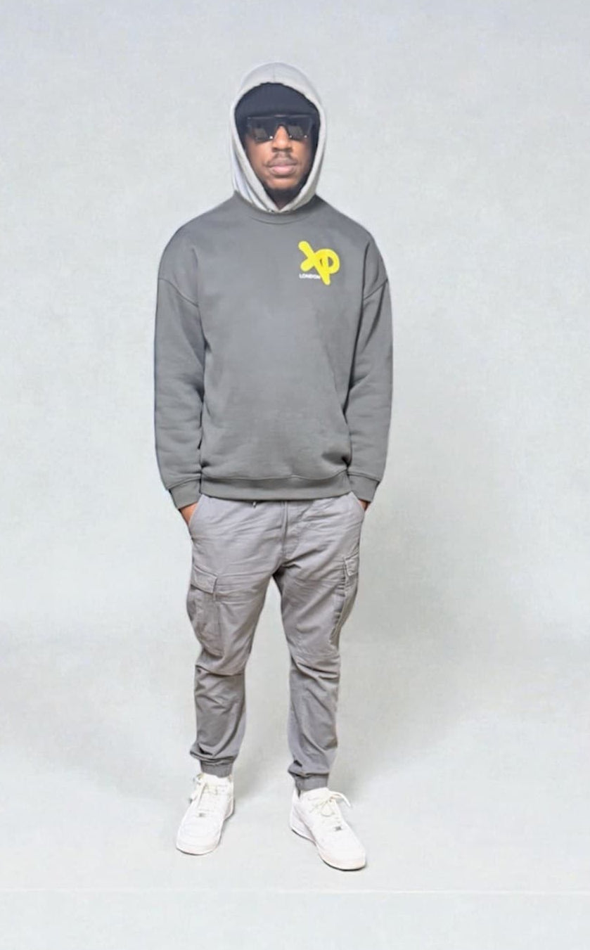 Model wearing grey XP London sweatshirt with yellow logo, styled with grey cargos