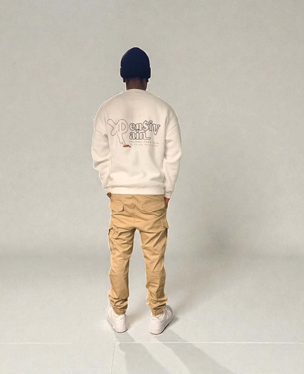 Back view of model wearing white XP London sweatshirt with XPensiv Pain graphic.